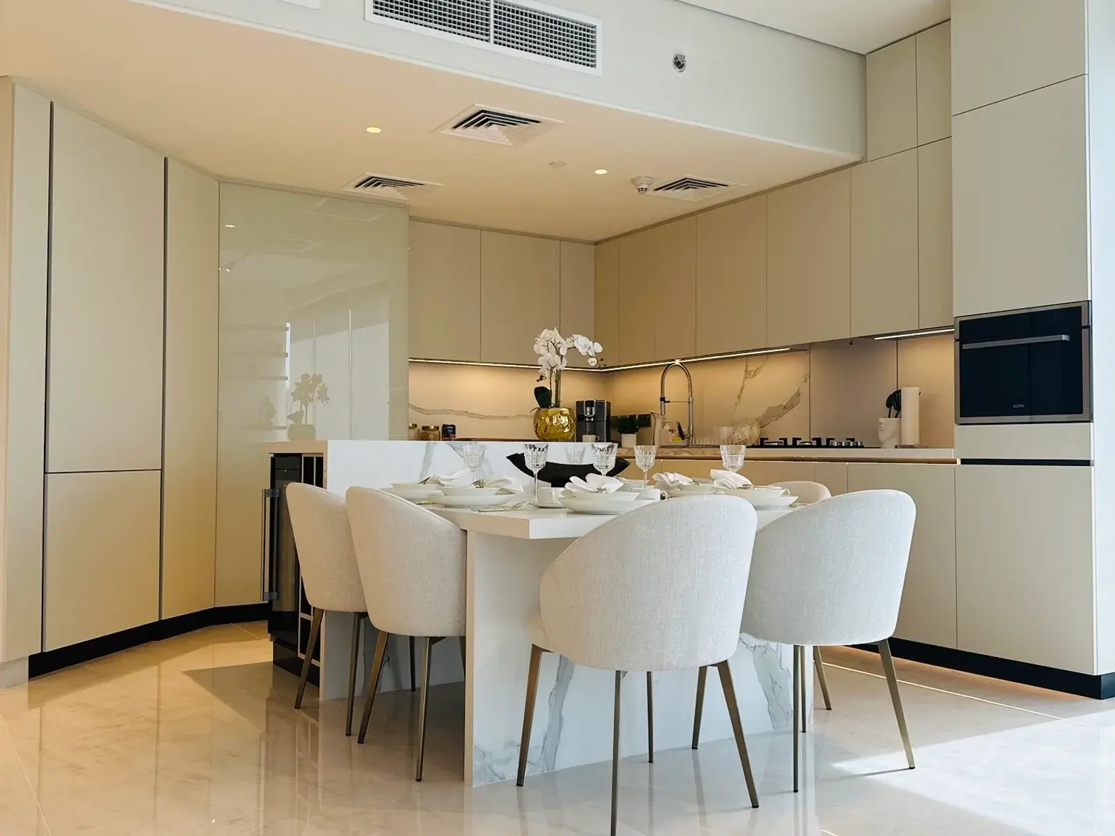 Dining table and upholstered chairs in front of a handleless kitchen run