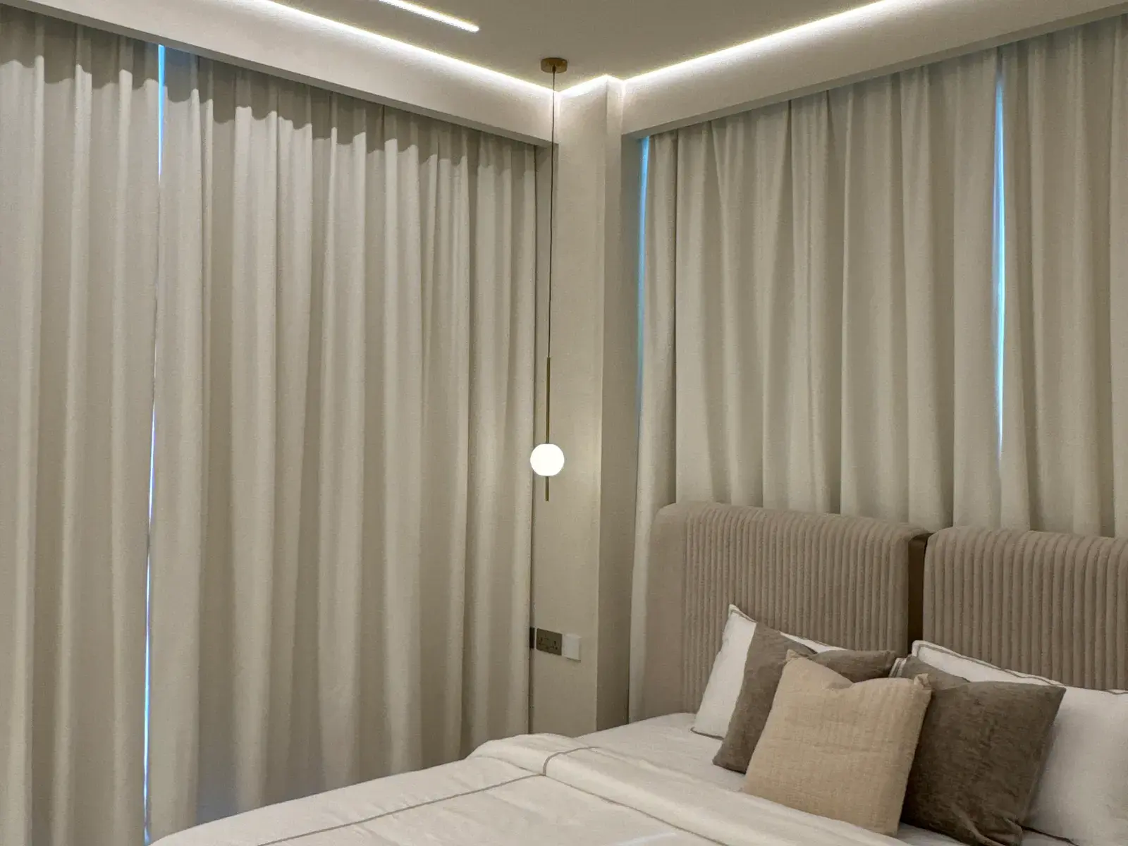 Bedroom with a fluted upholstered headboard and a dropped glass pendant