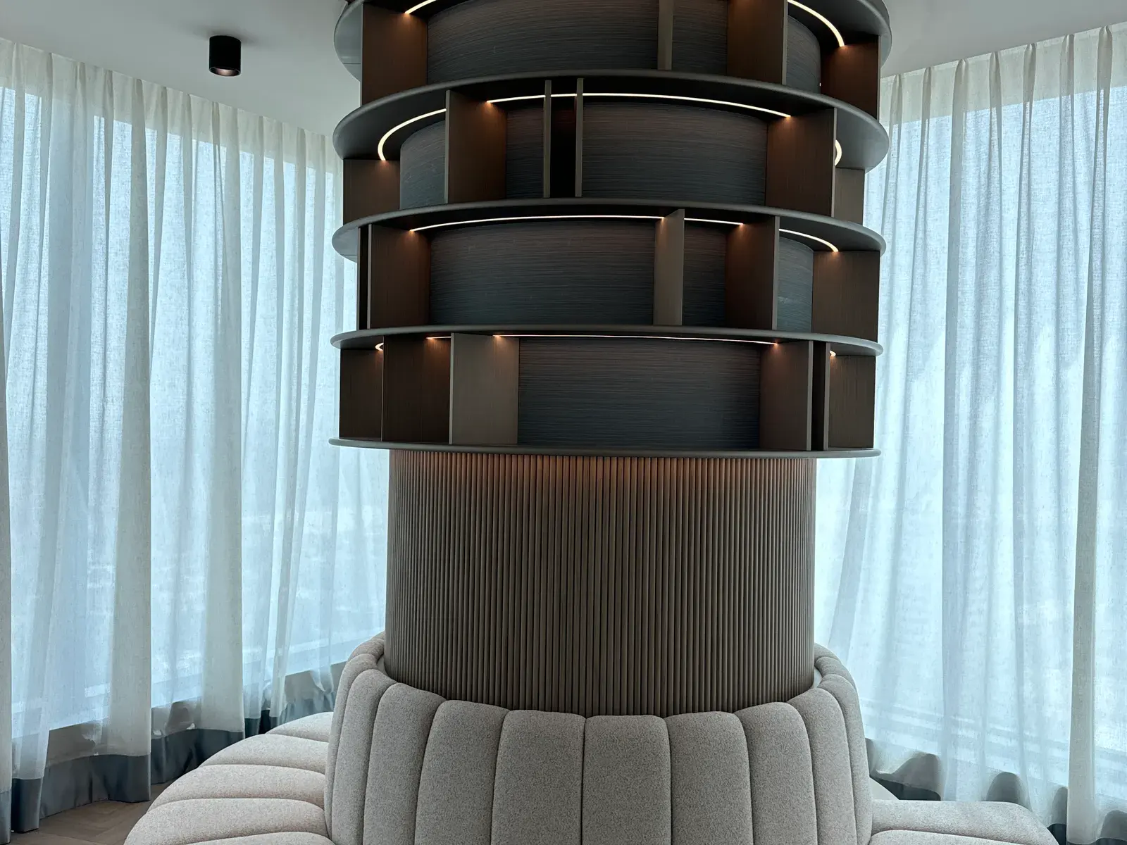 Curved bar in tinted timber with stacked shelving above a fluted base