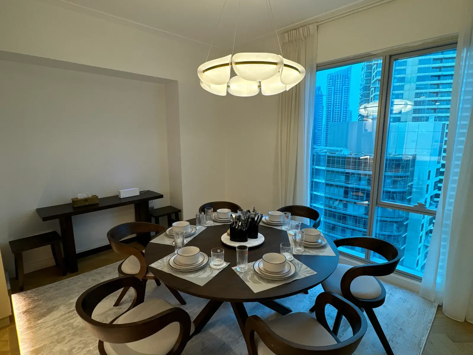 Round dining table and sculptural pendant against Marina glazing