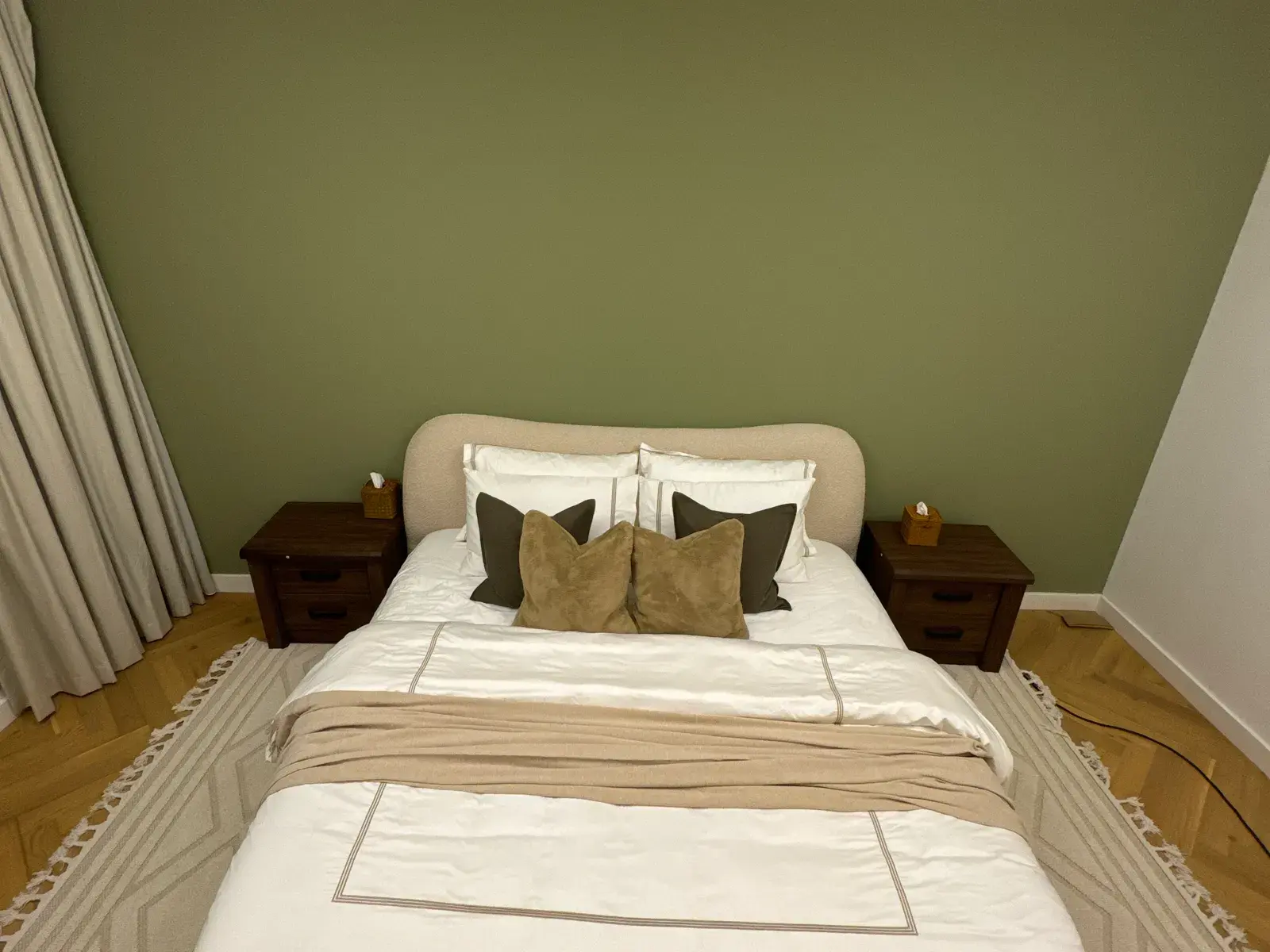Guest bedroom with an olive green feature wall and timber bedsides