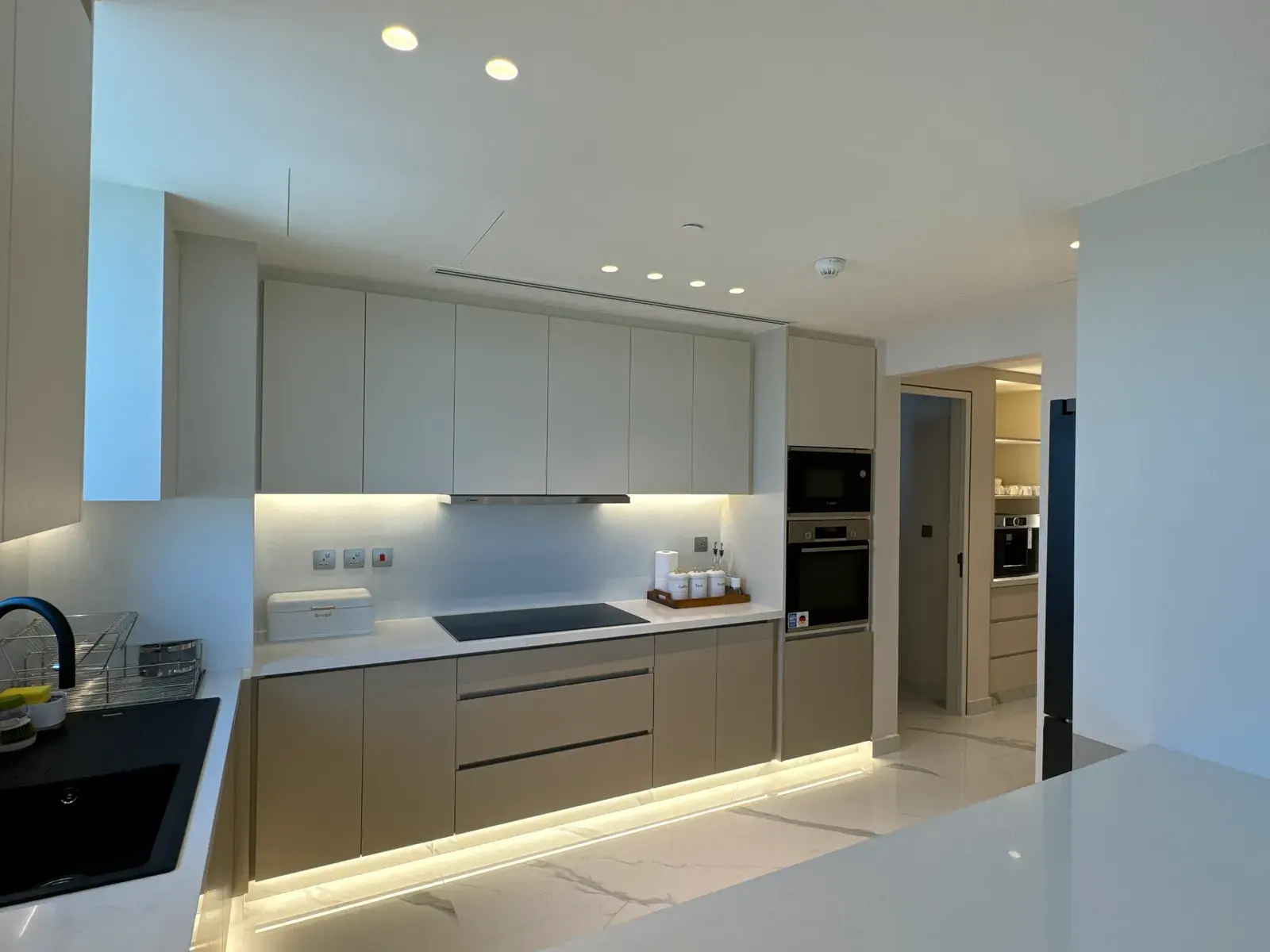 Handleless kitchen in soft grey with a lit plinth and integrated appliances