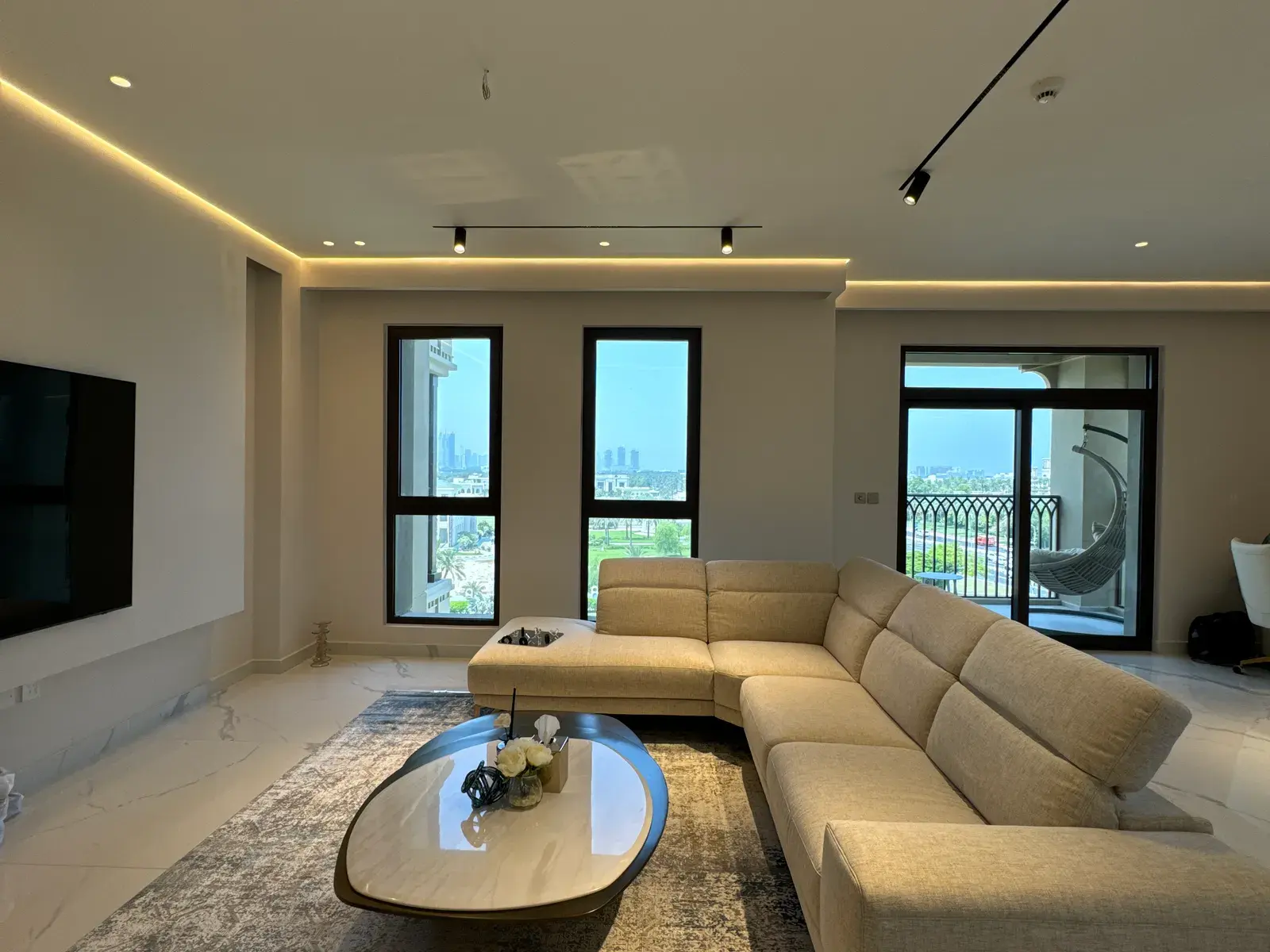 Living room with a sectional sofa, track lighting and balcony glazing