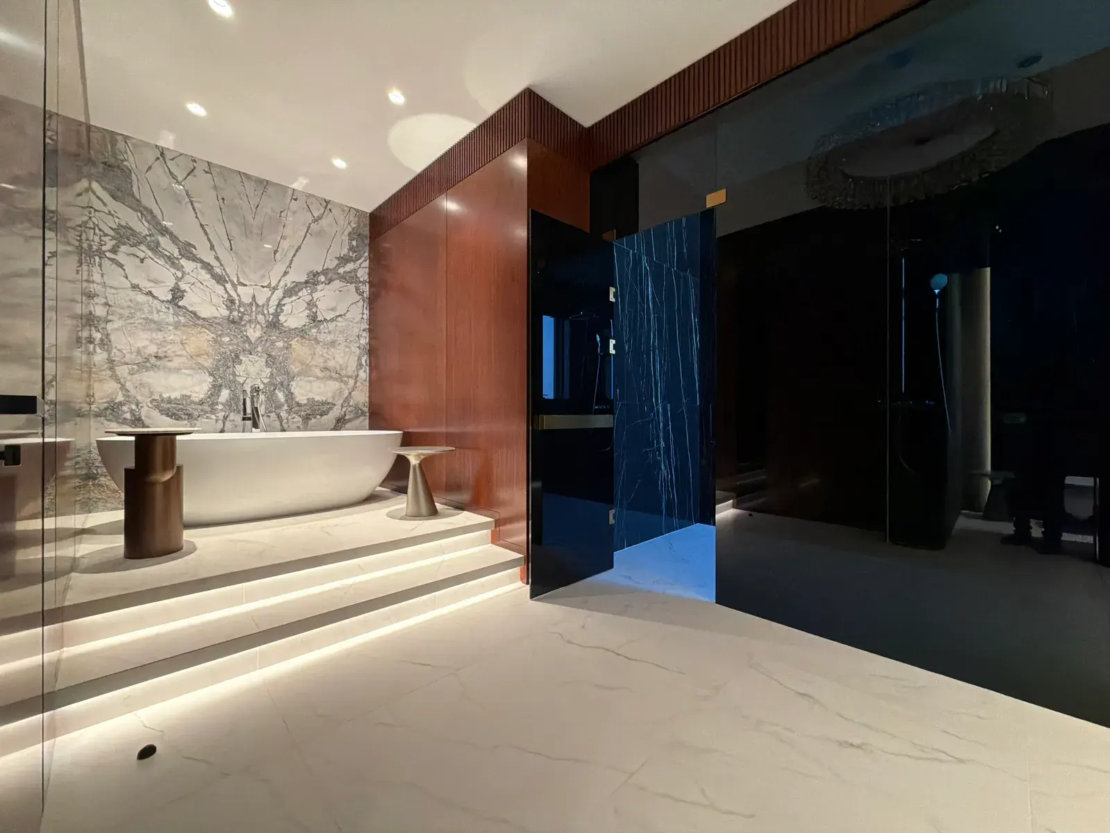 Freestanding bath on a book-matched marble plinth with mahogany panelling