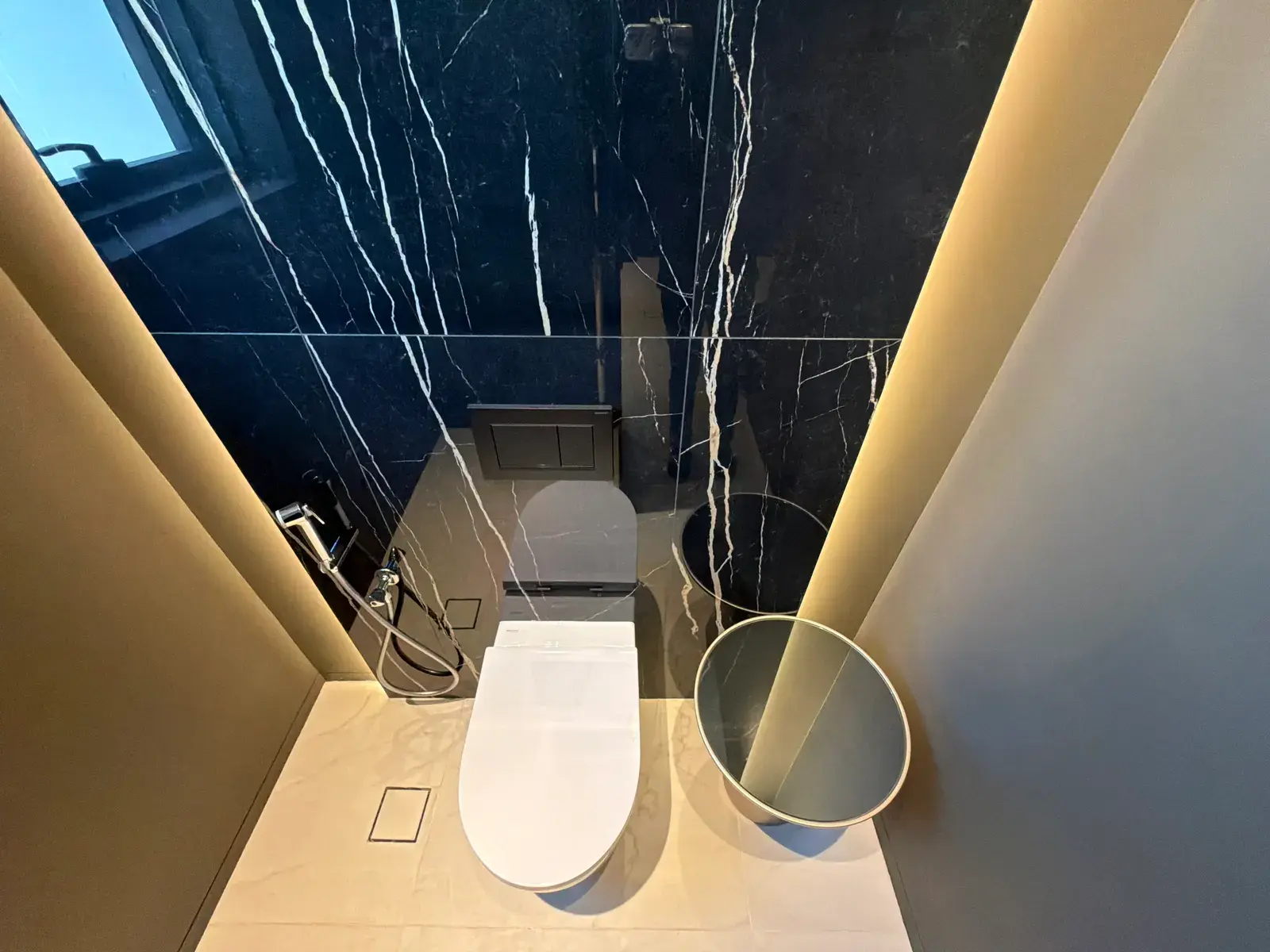 Guest bathroom in black marble with brass fittings and concealed lighting