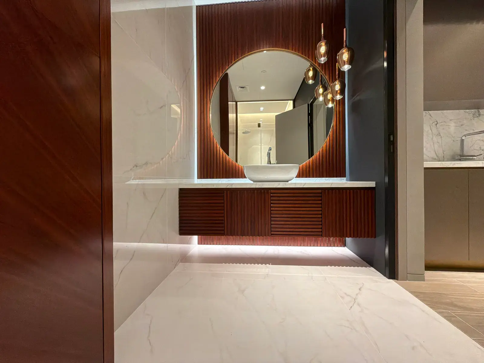 Bathroom with mahogany panelling, round mirror and sculptural pendant