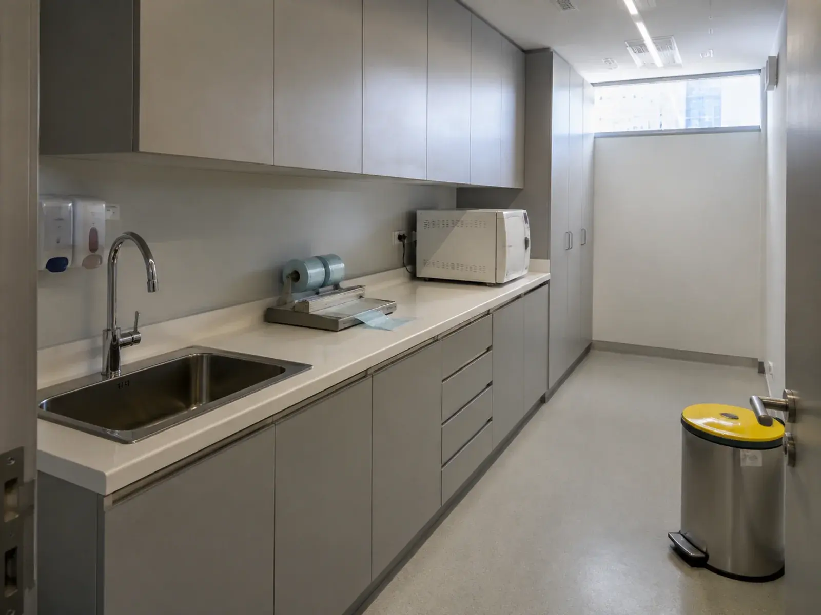 Clinic sterilisation room with a one-way dirty-to-clean bench run, stainless sink and autoclave