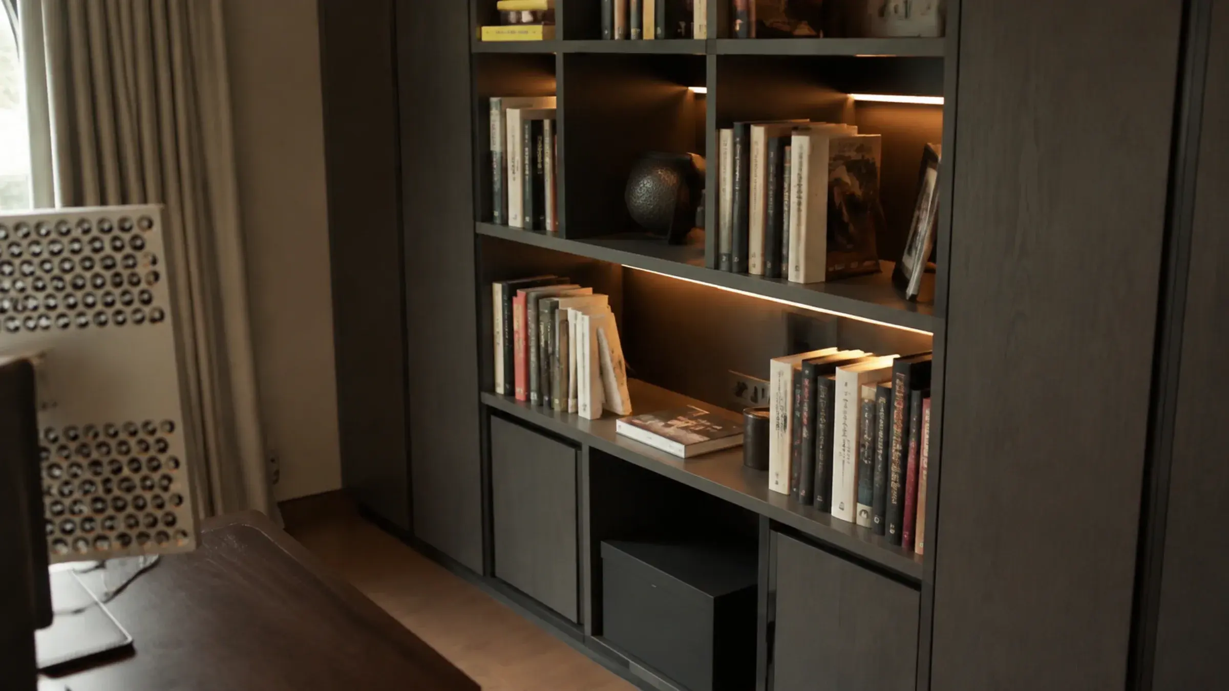 Built-in bookshelf beside a desk with mismatched book spines and a small framed photo turned partly away from camera