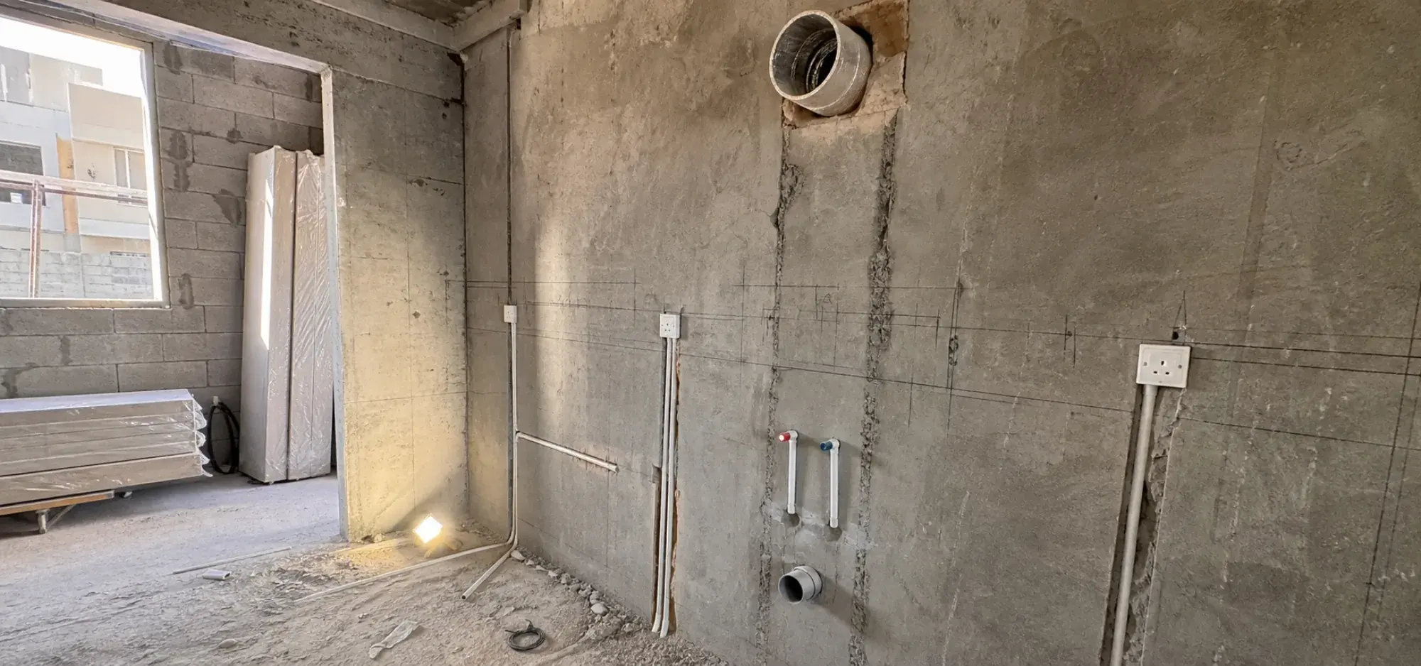 Kitchen first fix in Dubai with capped pipework, socket back boxes and extractor ducting set out on the wall
