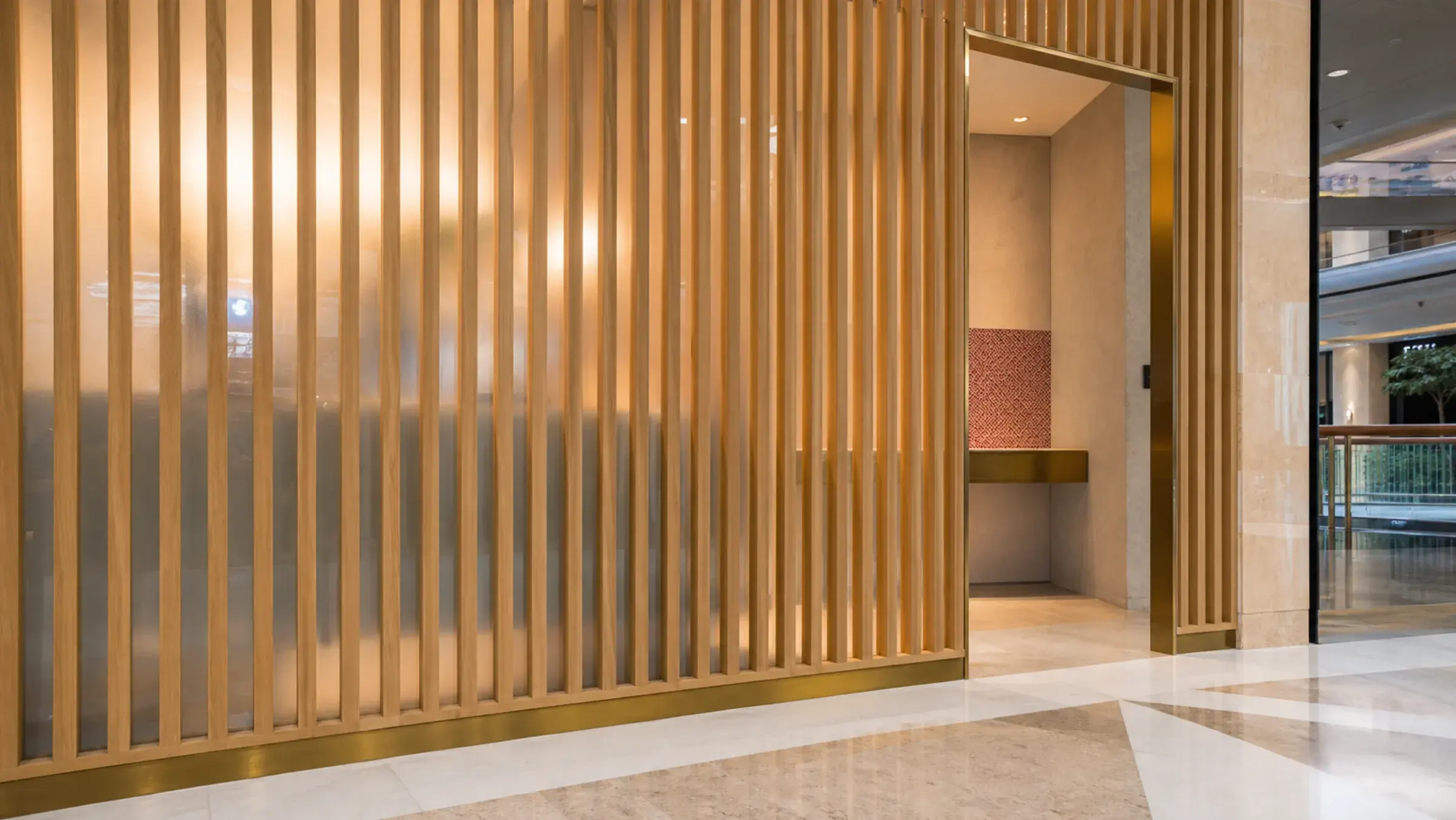 Pale oak fins and etched glazing screen the entrance to a private ladies salon in a Dubai mall