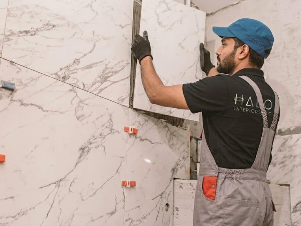 Halo installer setting a large-format marble slab against a wall with levelling clips in Dubai