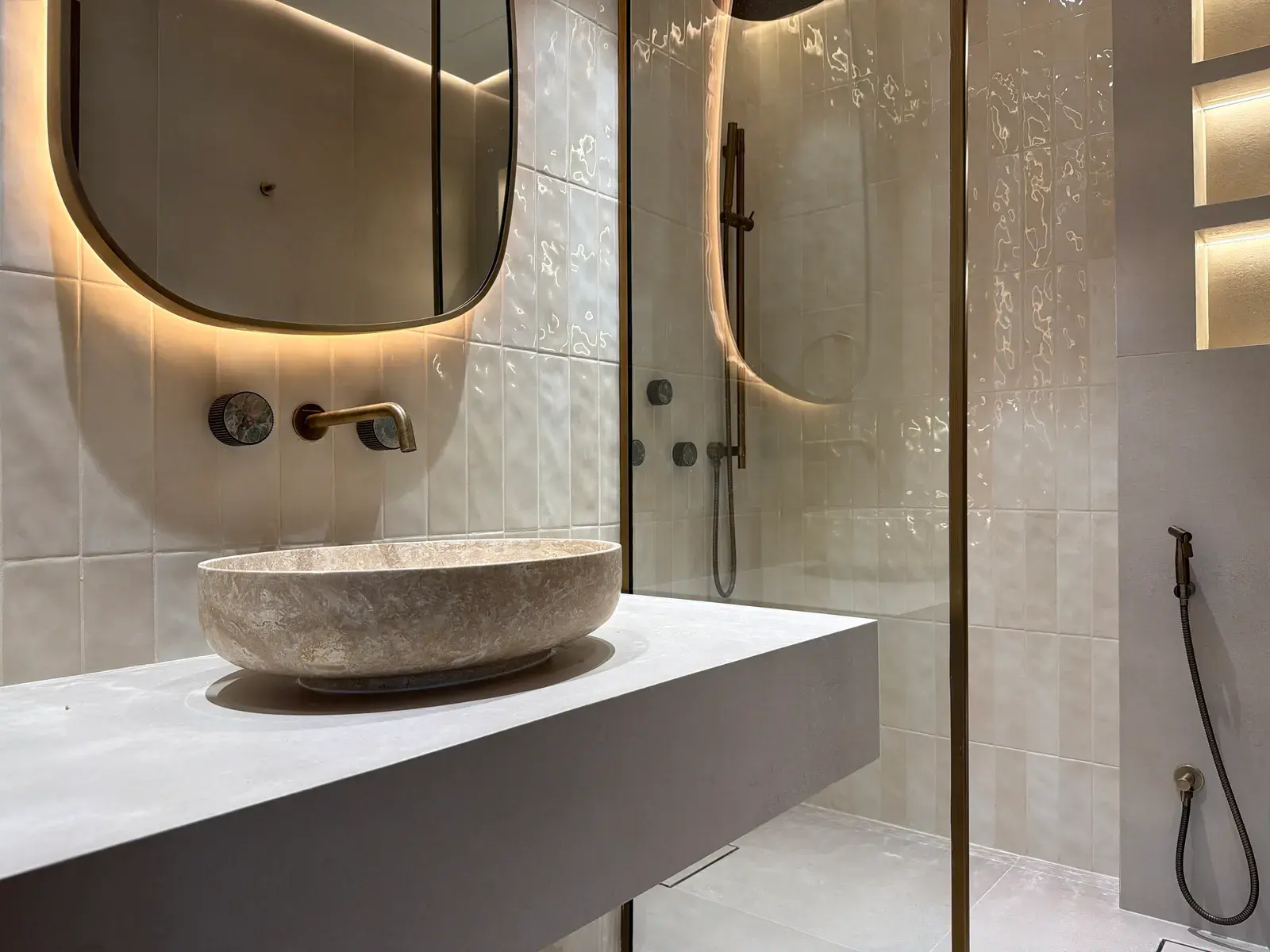 Carved stone basin on a travertine shelf beneath an arched mirror