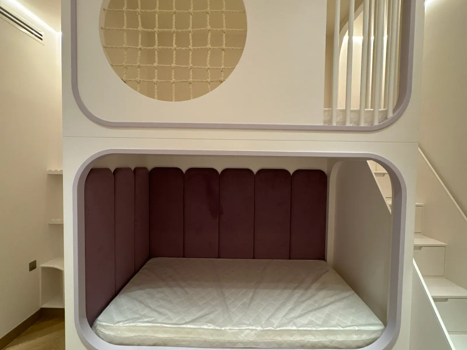 Built-in bed nook with an upholstered velvet back panel and integrated steps