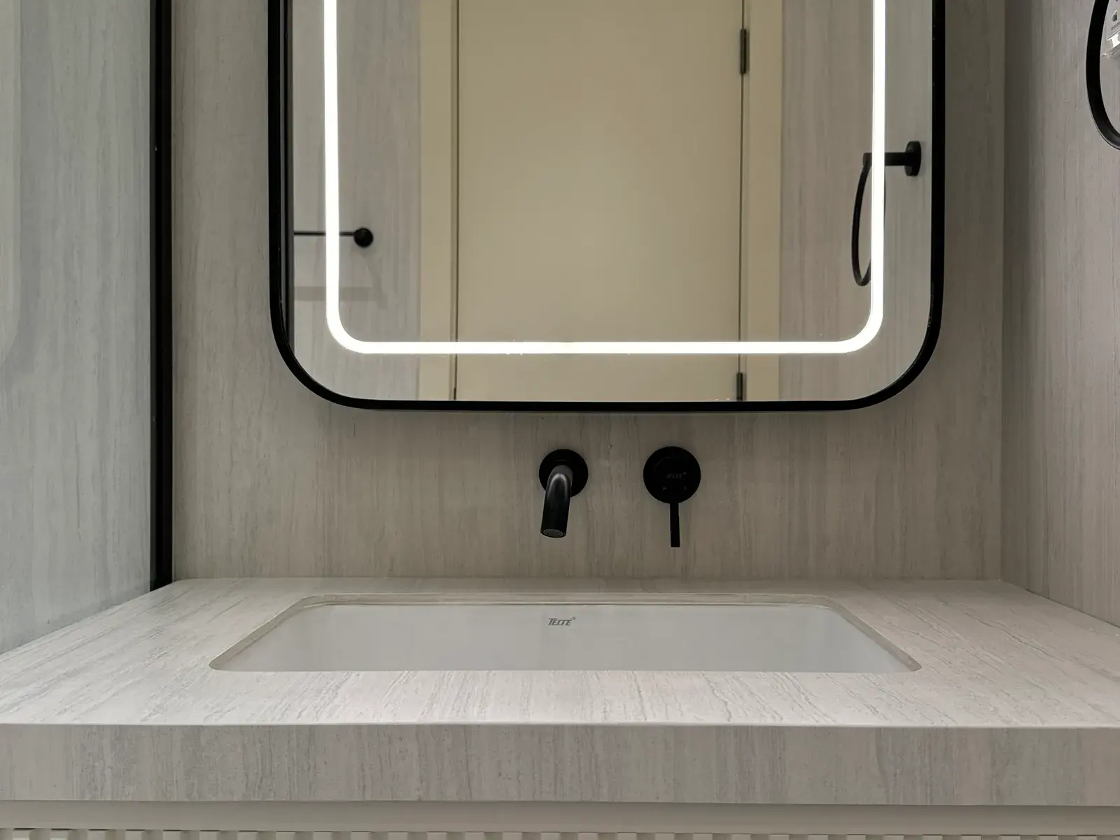 Sunken bath set into a stone-effect surround beneath a backlit mirror
