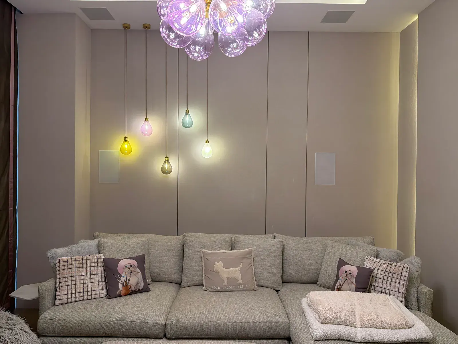 Living room with a long sofa, backlit wall panelling and a cluster pendant