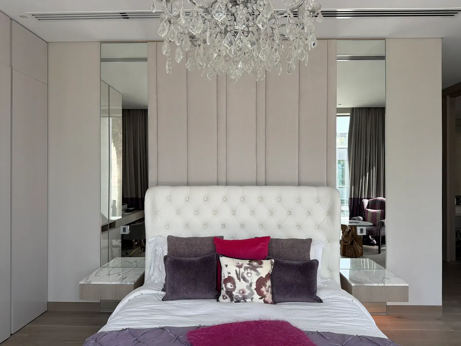Principal bedroom with a tufted headboard wall and mirrored wardrobe doors