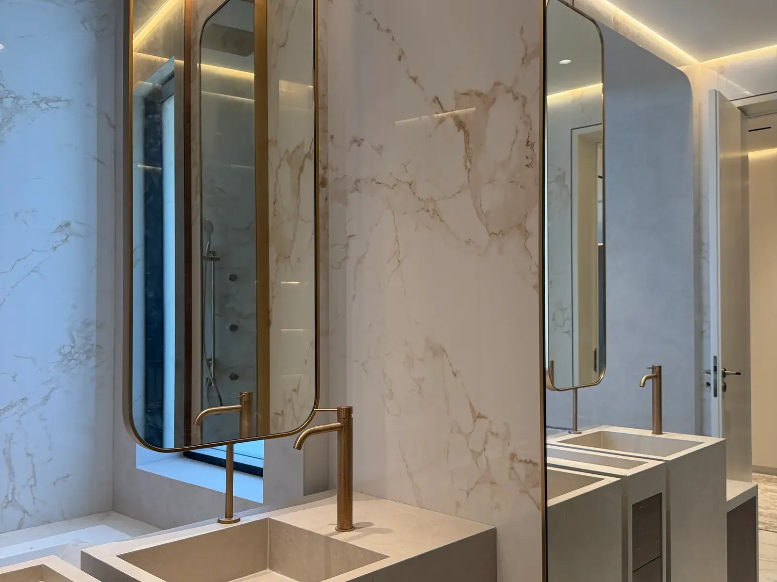 Twin marble vanities under brass-framed mirrors