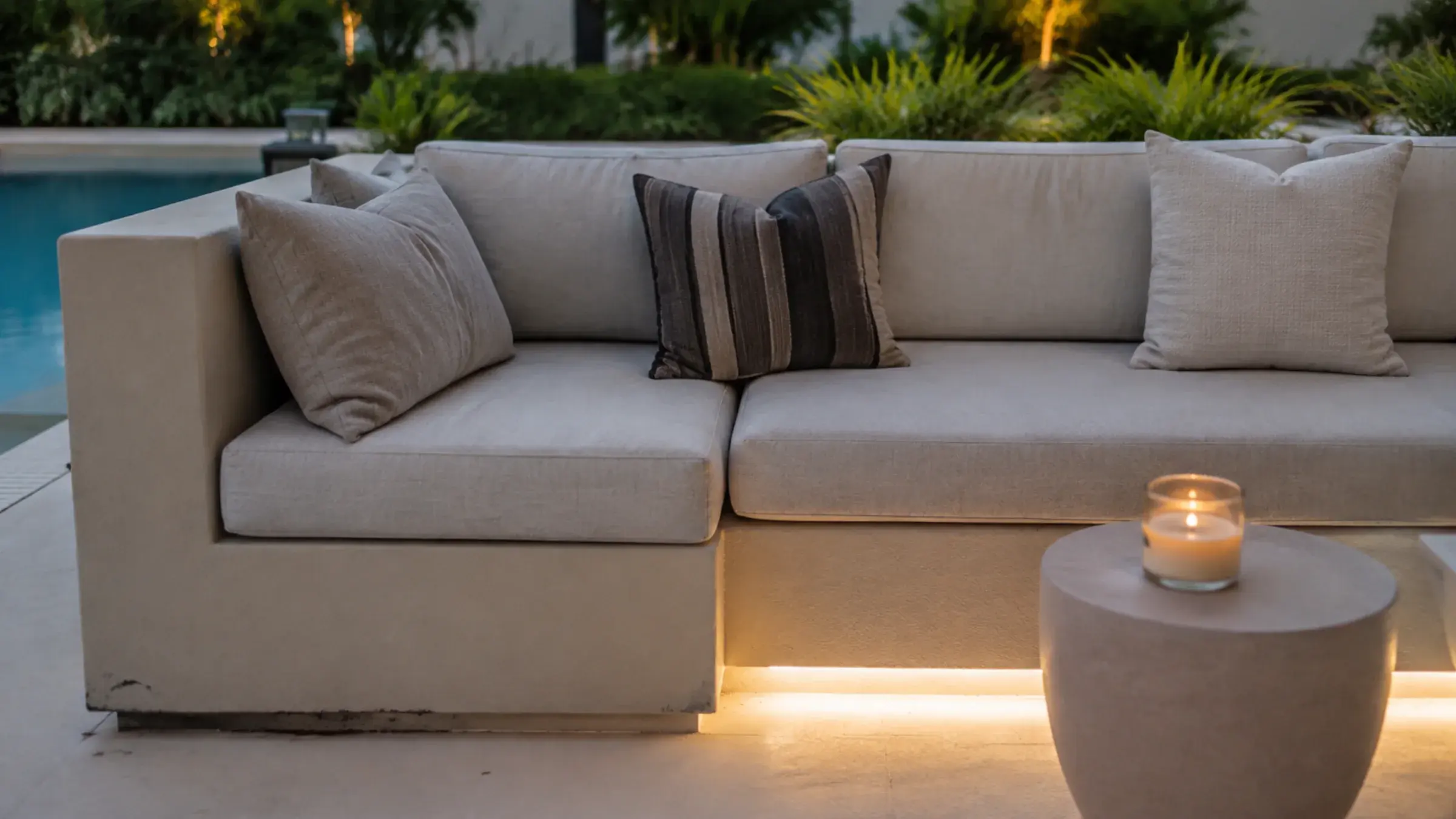 Built-in rendered blockwork seating structure on a villa terrace with deep cushions and warm step lighting at dusk