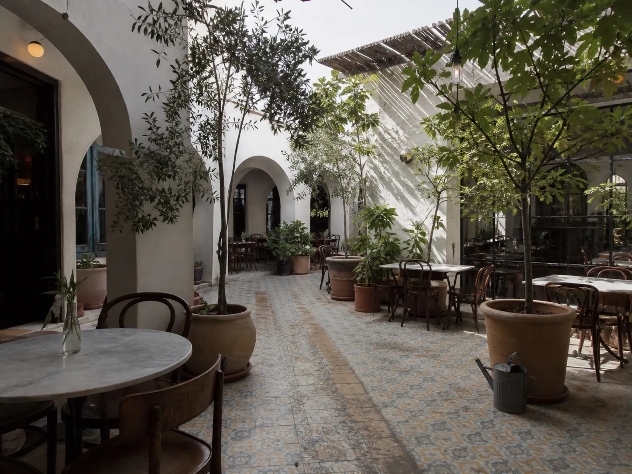 Levantine courtyard restaurant with patterned floor tile, planting and arched openings