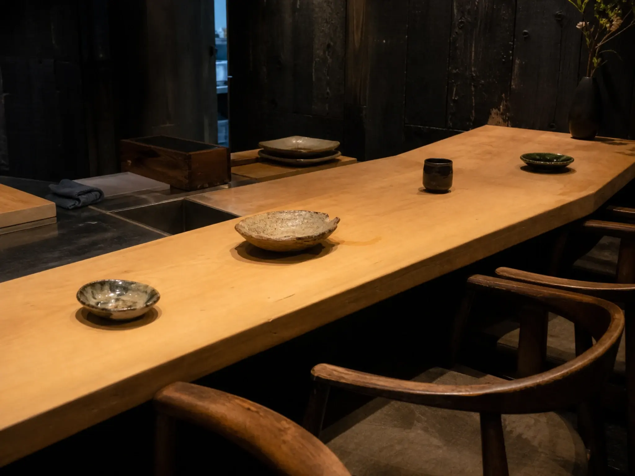 Japanese omakase counter in hinoki timber with focused lighting and dark surrounding walls
