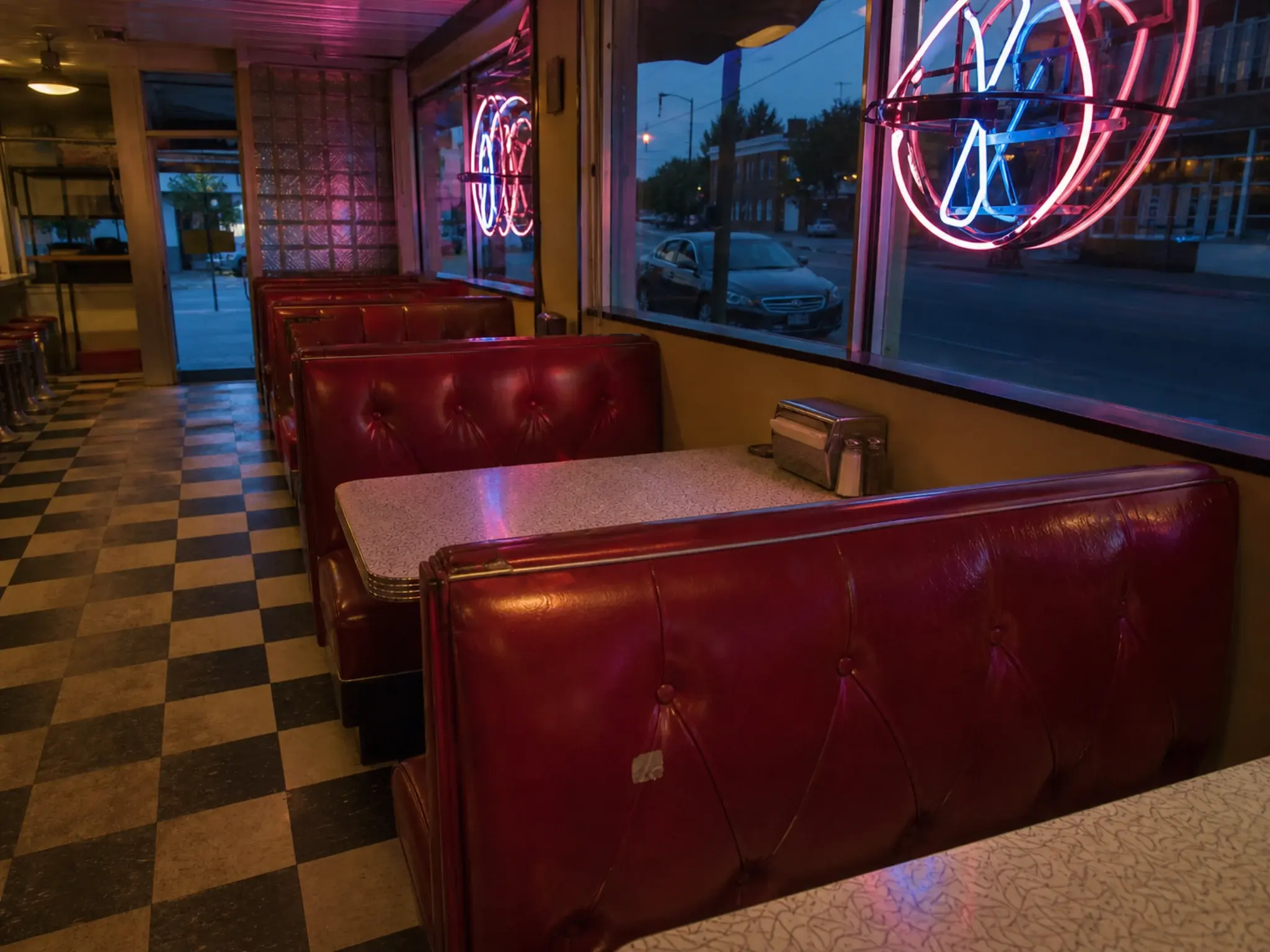 Retro American diner interior with red vinyl booths, chrome trim, chequerboard floor and neon lighting