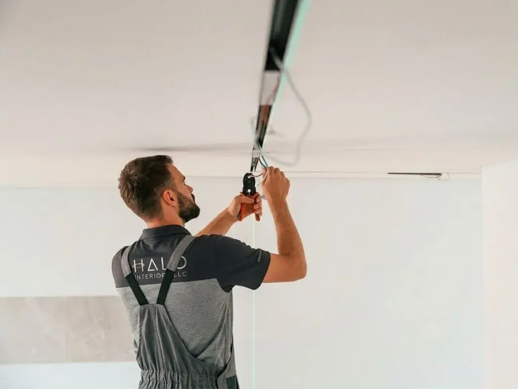 Halo technician releasing a stretch ceiling membrane from its perimeter track for void access