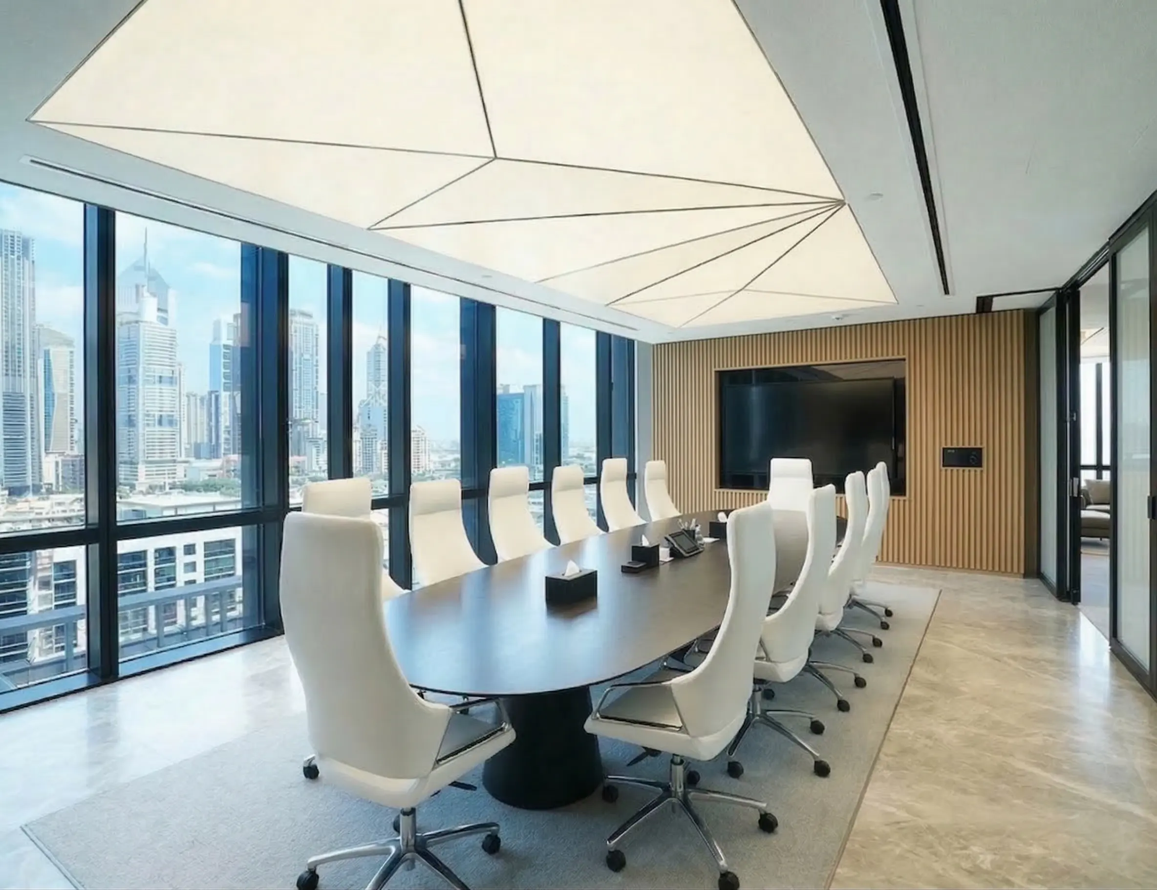 Faceted translucent stretch ceiling over a boardroom with floor-to-ceiling Dubai skyline glazing