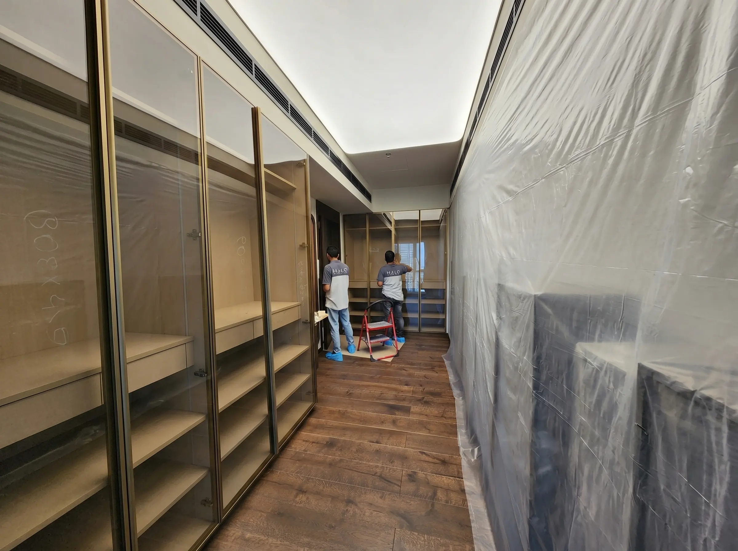 Stretch ceiling installation in progress in a Dubai corridor with the finished areas sheeted