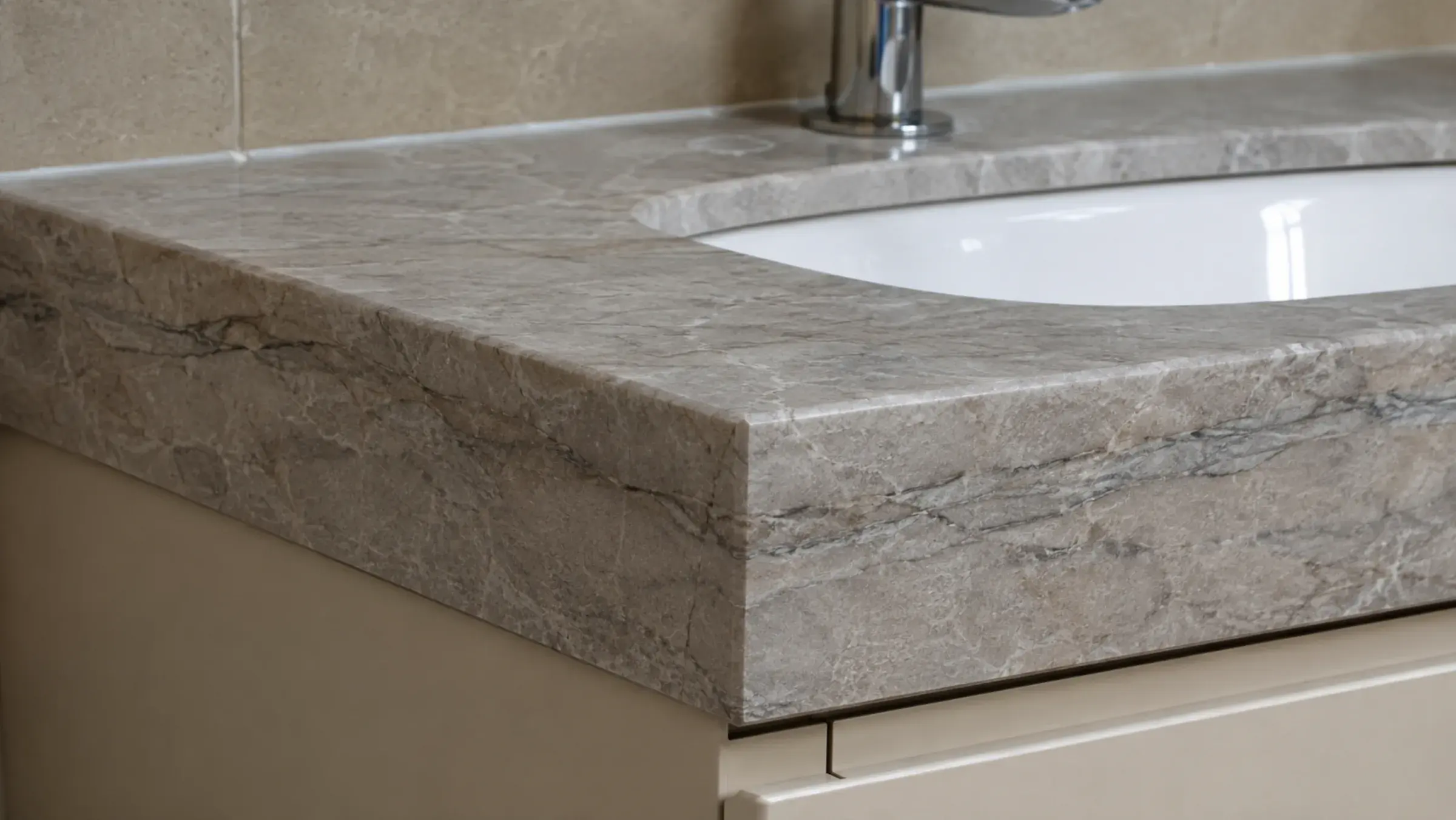 Close-up of a grey marble vanity top showing its mitred edge and undermount basin reveal