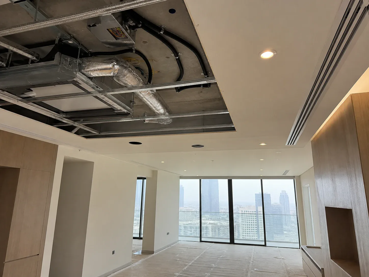 Coordinated AC ductwork, electrical conduits, ceiling framing and recessed lighting in a Dubai apartment renovation