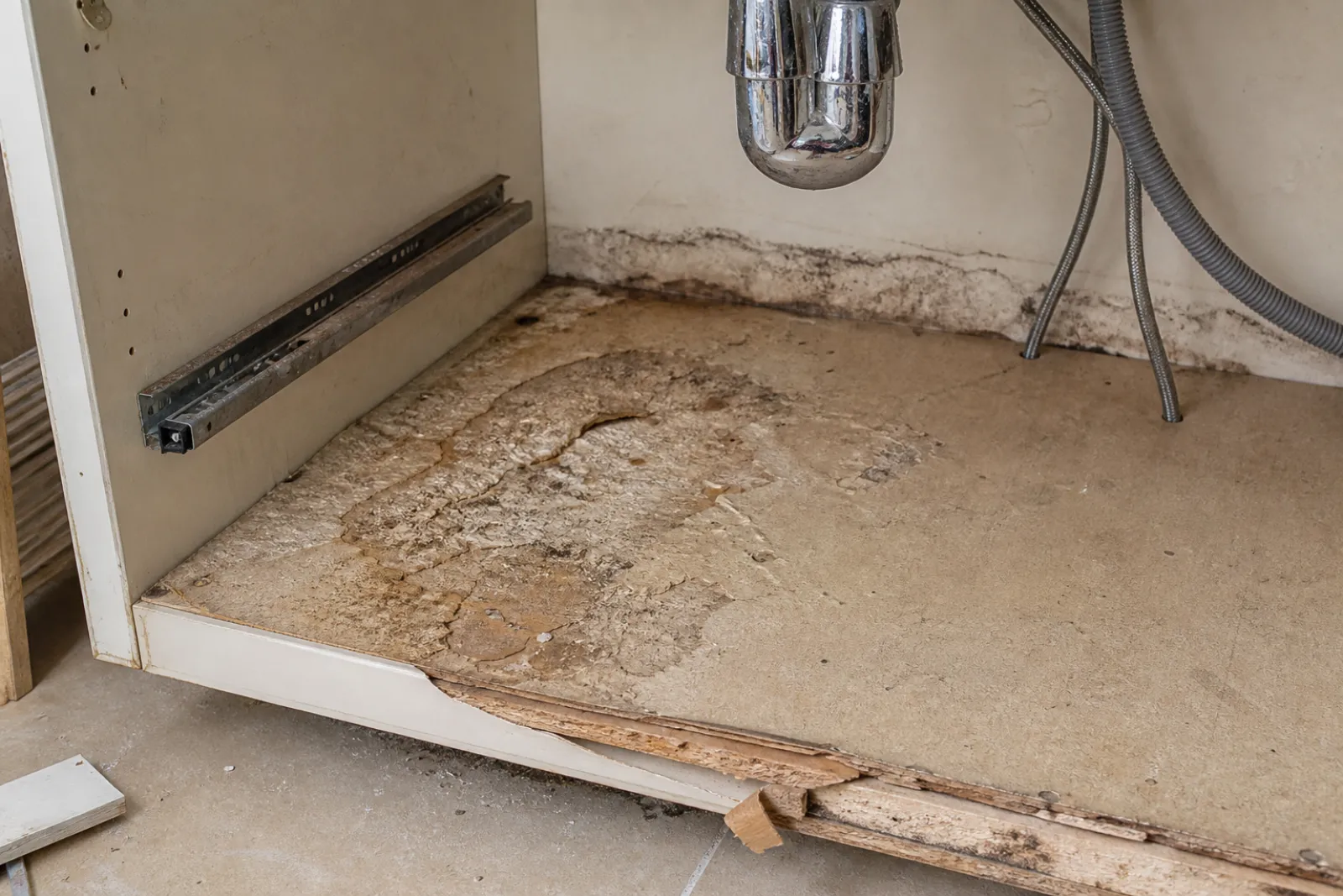 Swollen particleboard and lifted edge banding inside a failed sink cabinet