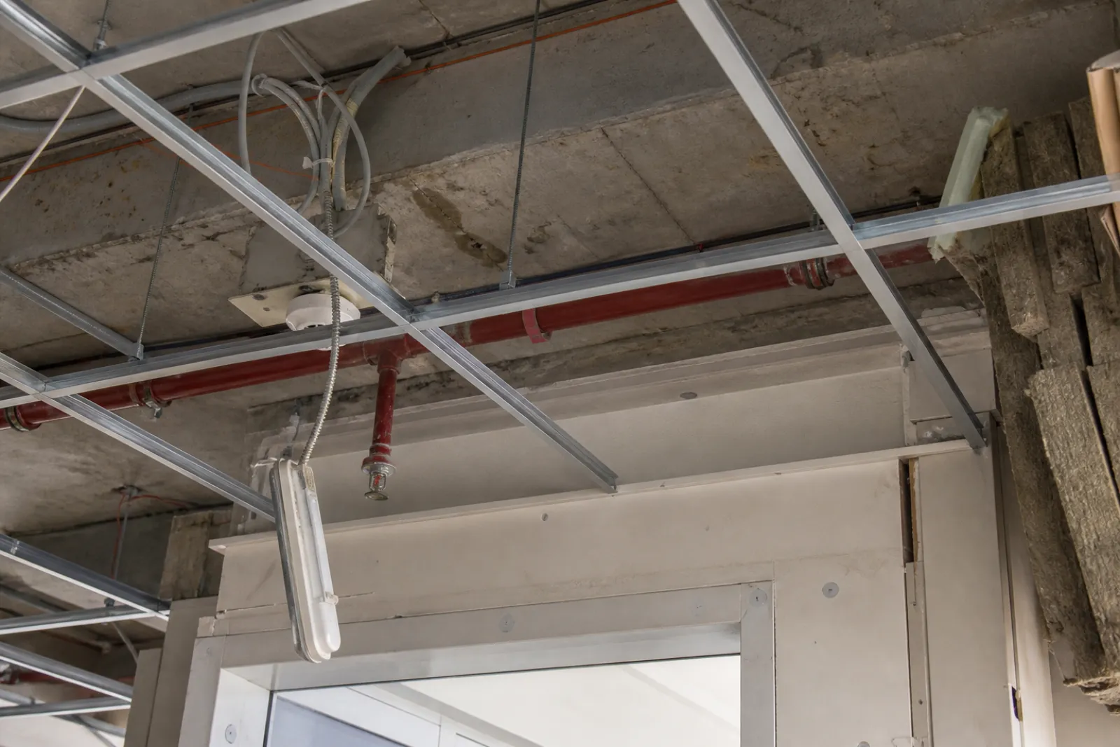 Sprinkler pipework, detector base and emergency lighting in an office ceiling void