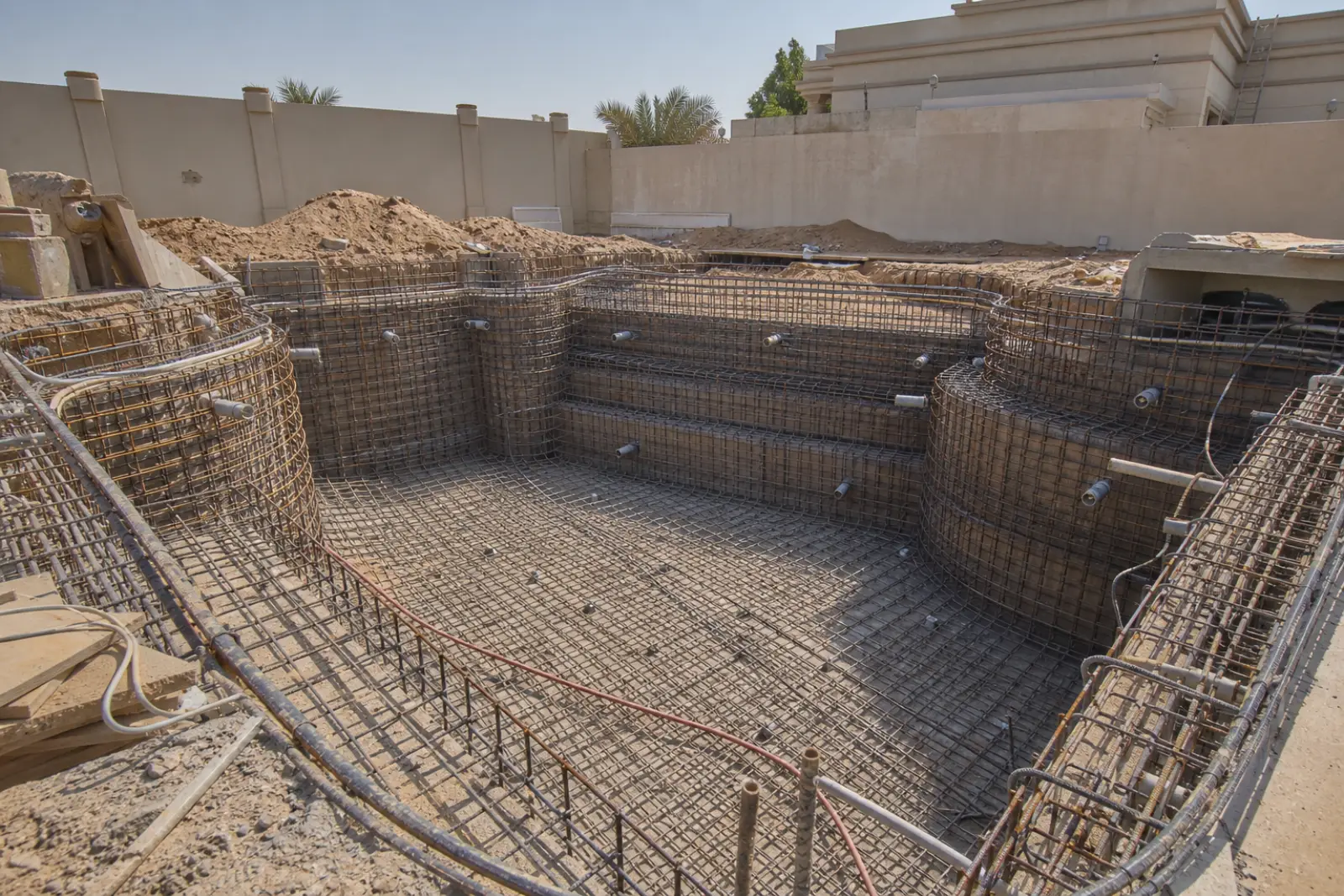 Steel reinforcement cage formed to a pool shell before gunite application