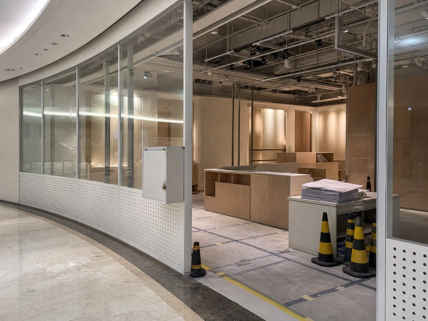 Empty Dubai mall retail unit during final fit-out coordination, behind a temporary site barricade