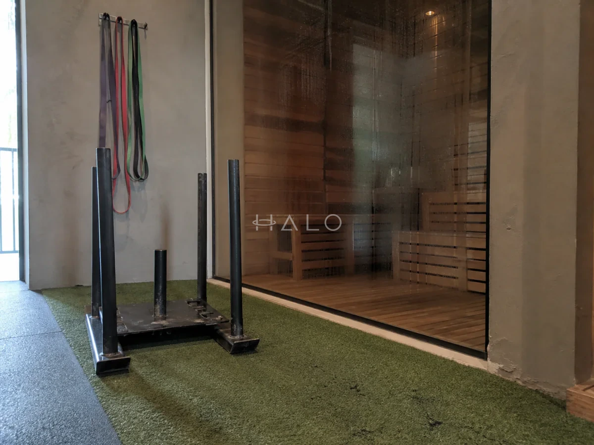 Fitness recovery zone with artificial turf, training sled and a glazed sauna partition