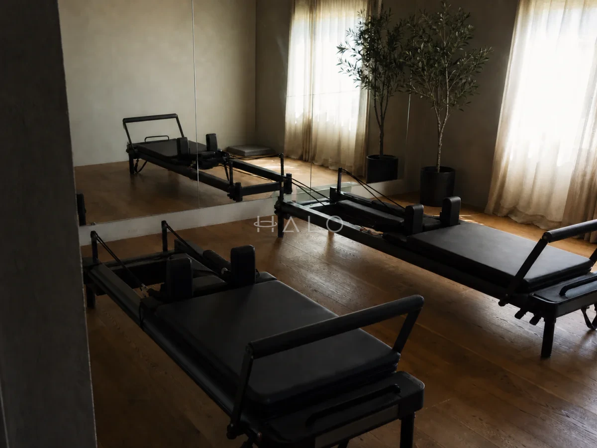 Private reformer studio with two Pilates machines, oak flooring and an off-axis mirrored wall